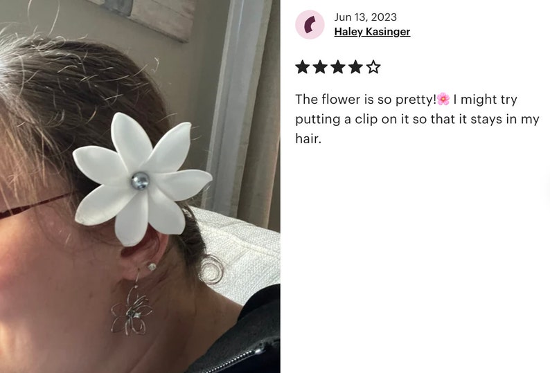 May include: A white flower hair clip with a pearl center. The flower is attached to a person's hair. The flower is so pretty! I might try putting a clip on it so that it stays in my hair.