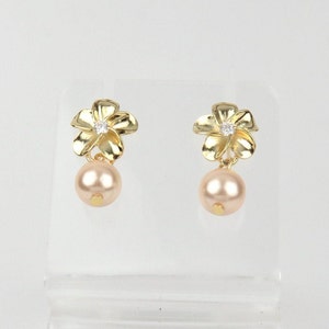 May include: A pair of gold flower-shaped earrings with a single pearl dangling from each flower.