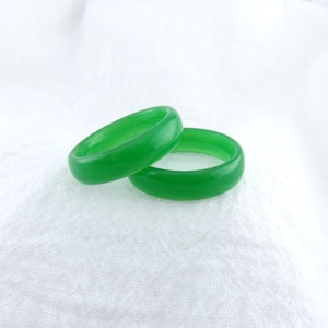 May include: Two green jade rings, stacked on top of each other, on a white background.