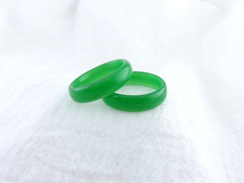 May include: Two green jade rings, stacked on top of each other, on a white background.