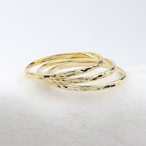May include: Four gold-toned stacking rings with a hammered texture.