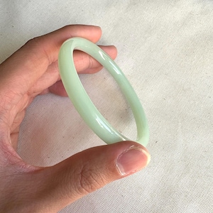Pode incluir: Um bracelete de jade verde claro. O bracelete é liso e polido.