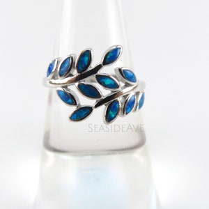 May include: A silver ring with a blue opal leaf design. The ring is on a display stand.  Seasideaave.