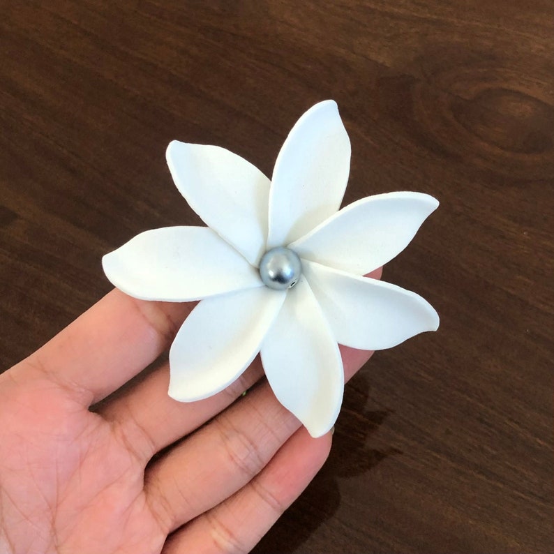 May include: A white flower with five petals and a silver bead in the center.