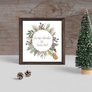 Könnte beinhalten: Ein gerahmter Druck mit einer Aquarell-Illustration eines Kranzes aus Kiefernästen und Beeren. Der Kranz ist von einem Kreis mit dem Text "Das erste Weihnachten als Familie Brand" und einem Etikett mit dem Jahr "2019" umgeben.