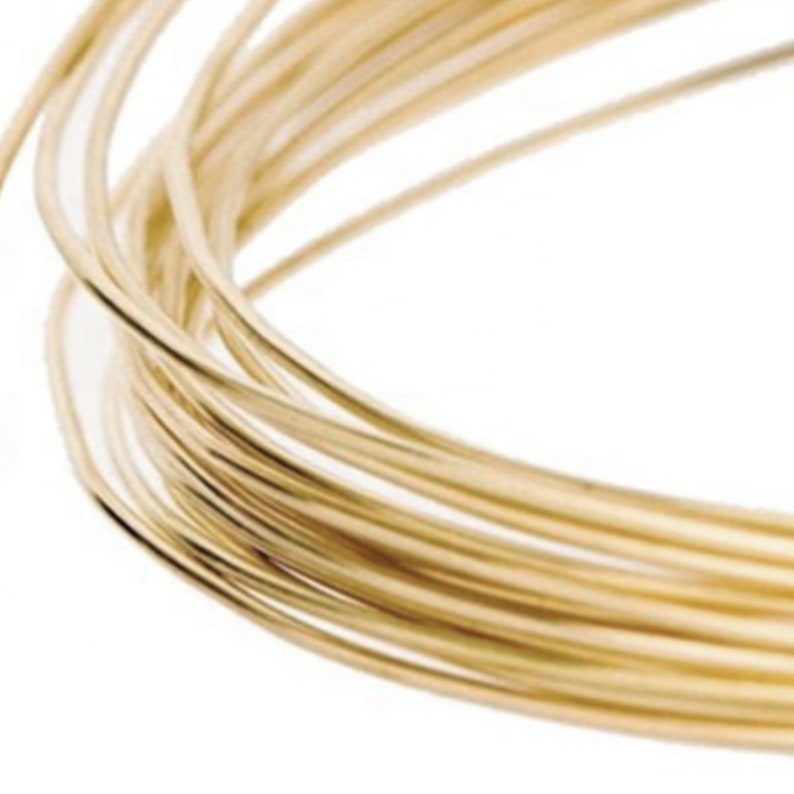 May include: A close-up of a spool of gold-colored wire. The wire is wound tightly together, creating a smooth, shiny surface.
