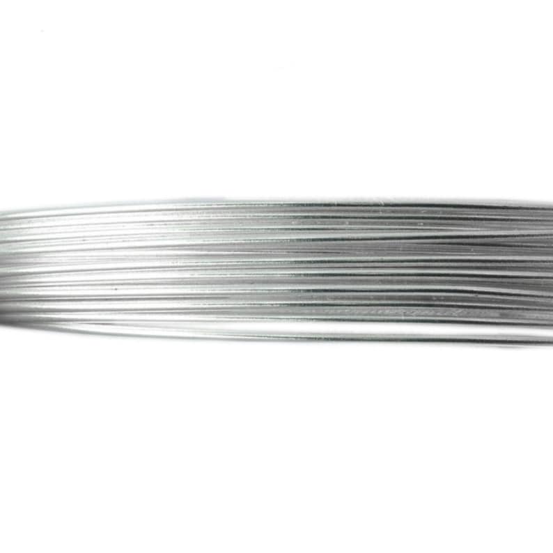 May include: Close-up of a bundle of silver-colored wire, tightly wound together. The wire appears to be made of a shiny, metallic material, and the individual strands are clearly visible. The background is plain white.
