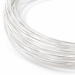 Pu&ograve; includere: Primo piano di una bobina di filo lucido color argento. Il filo &egrave; avvolto strettamente, creando una forma circolare. Il metallo brillante riflette la luce, evidenziando la consistenza liscia del filo. Lo sfondo &egrave; bianco.