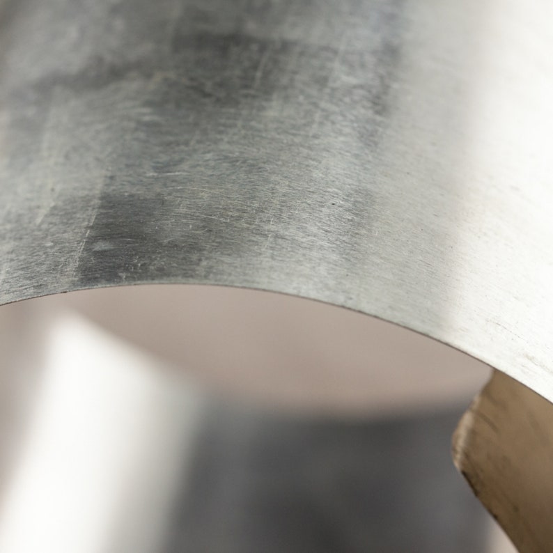 May include: Close-up of a silver metal sheet, showing the texture and slight curve of the metal.
