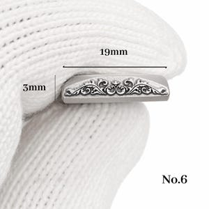 Op de afbeelding: Een kleine, rechthoekige metalen stempel met een sierlijk bloemmotief. De stempel is 1,9 cm lang en 3 mm breed. Het nummer "No.6" staat rechtsonder gedrukt.