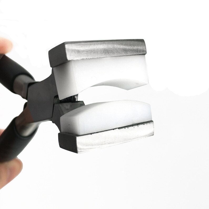 May include: Close-up of a silver metal jewelry pliers with white plastic pads. The pliers are open and the pads are facing the camera.