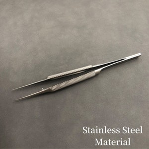 K&ouml;nnte beinhalten: Edelstahl-Pinzette mit strukturierten Griffen und spitzen Spitzen. Die Griffe haben ein Rautenmuster f&uuml;r besseren Halt. Der Text "Stainless Steel Material" ist im Bild sichtbar.