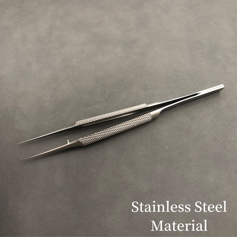 K&ouml;nnte beinhalten: Edelstahl-Pinzette mit strukturierten Griffen und spitzen Spitzen. Die Griffe haben ein Rautenmuster f&uuml;r besseren Halt. Der Text "Stainless Steel Material" ist im Bild sichtbar.