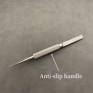 K&ouml;nnte beinhalten: Eine silberfarbene Ahle mit einem strukturierten, rutschfesten Griff. Die Ahle hat eine scharfe, spitze Spitze und ein flaches, rechteckiges Ende. Dieses Pr&auml;zisionswerkzeug ist f&uuml;r Detailarbeiten konzipiert und eignet sich f&uuml;r verschiedene Bastel- und Reparaturarbeiten.