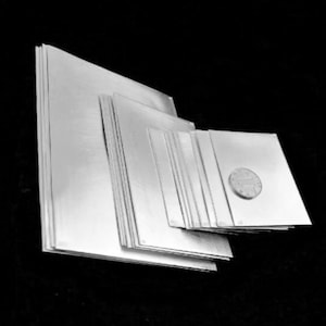May include: A stack of silver sheets of varying sizes, with the smallest sheet being about the size of a US quarter.