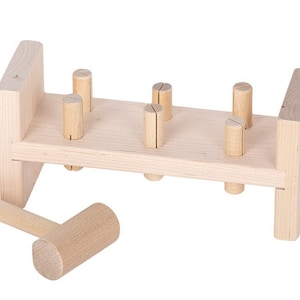 May include: A wooden toy hammer and peg set. The set includes a wooden hammer and a wooden base with five pegs that can be hammered in and out.