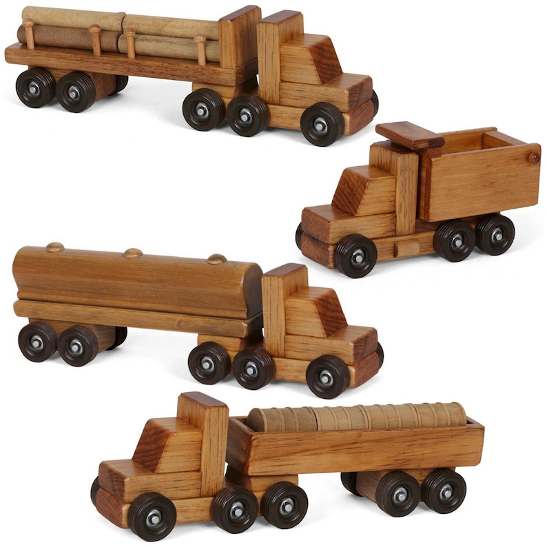 Pu&ograve; includere: Set di quattro camion giocattolo in legno con diversi rimorchi. I camion sono in legno naturale e hanno ruote dipinte di marrone. I rimorchi includono un trasportatore di tronchi, un camion ribaltabile, un autocisterna e una piattaforma con barili.