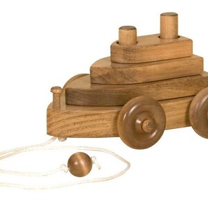 May include: A wooden toy boat with a pull string and stacking rings. The boat has two wheels and is painted in a natural wood color.