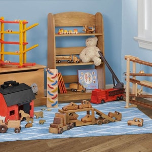 May include: A wooden toy playroom with a red toy barn, a wooden toy truck carrying smaller toy cars, a wooden toy fire truck, a wooden toy helicopter, a wooden toy train, a wooden toy spiral, a wooden toy shelf with a teddy bear, a wooden toy ramp, and a wooden toy chest.