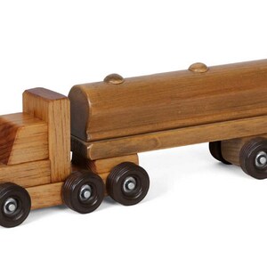 Pu&ograve; includere: Un camion giocattolo di legno con un rimorchio cisterna di legno marrone. Il camion ha quattro ruote e il rimorchio ne ha due. Il camion e il rimorchio sono fatti di legno naturale.