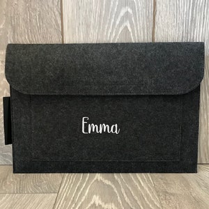 May include: A dark grey felt laptop sleeve with a white embroidered name "Emma" on the front.