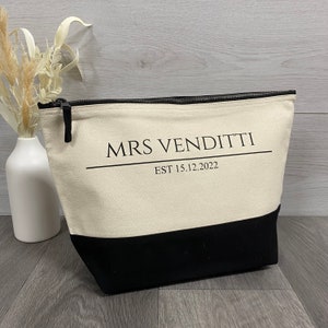 May include: A black and white canvas zippered pouch with the text "MRS VENDITTI EST 15.12.2022" printed on the front.