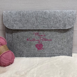 May include: Grey felt envelope with a pink embroidered design that says "Mom's Knitting Patterns" with a small image of a ball of yarn and knitting needles.