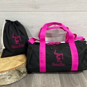 May include: Black gym bag with hot pink straps and a pink glitter design of a gymnast is printed with a personalised name option underneath. A smaller black drawstring bag with a similar design is also included in the image which can be purchased at an additional cost.
