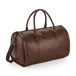 Pu&ograve; includere: Una borsa da viaggio in pelle marrone con manico superiore e tracolla. La borsa ha una chiusura a zip e un tiretto della zip dorato.