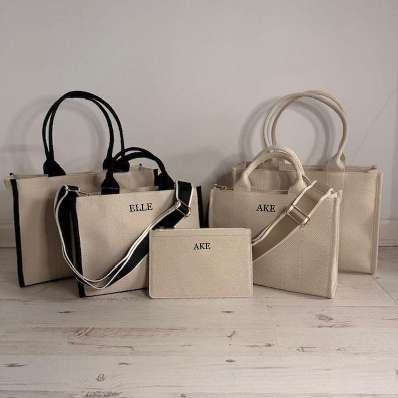May include: A collection of beige canvas tote bags and a matching pouch. The bags have black or beige handles and straps, with the names "ELLE" and "AKE" printed on them. The bags are of different sizes.