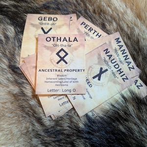 Puede incluir: Primer plano de una pila de cartas con diferentes runas y sus nombres. Las cartas están sobre un fondo de piel marrón. Las runas son OTHALA, GEBO, PERTH, NAUDHIZ y MANNAZ. Las cartas tienen texto que dice "ANCESTRAL PROPERTY", "Wisdom", "Inherent talent/Heritage", "Homecoming/Land of birth", "Heirlooms", "Letter: Long O", "Conne", "Sanctua", "Ward o", "Letter", "EED", "challenge", "Vival", "AZ" y "ing".