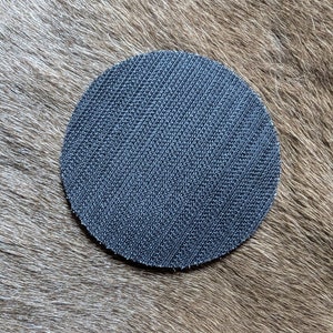 May include: A round, black sanding disc with a textured surface.