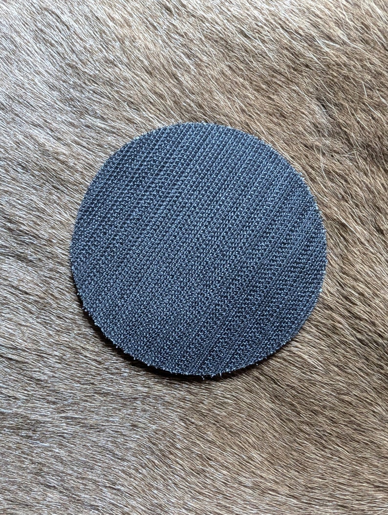 May include: A round, black sanding disc with a textured surface.