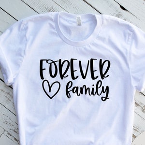 May include: White t-shirt with black text that reads "FOREVER family" with a heart symbol.