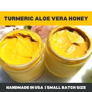 May include: Two glass jars filled with a bright yellow, creamy substance. The jars are labeled "TURMERIC ALOE VERA HONEY" in bold, yellow text on a black background. The bottom of the image reads "HANDMADE IN USA | SMALL BATCH SIZE".