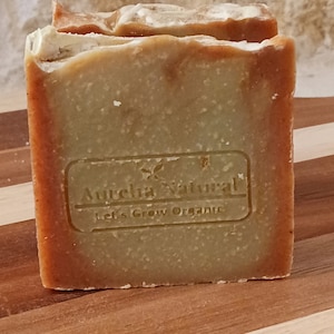 May include: A green and brown bar of soap with the text "Aurelia Natural Let's Grow Organic" on the front.