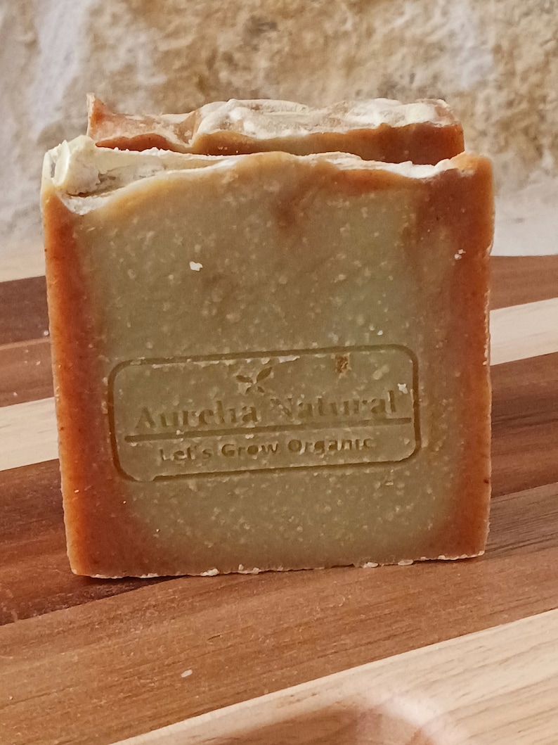 Op de afbeelding: Een groene en bruine zeep met de tekst "Aurelia Natural Let's Grow Organic" op de voorkant.