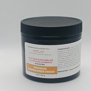 Op de afbeelding: Een zwarte pot Aurelia Natural Knuckles, Elbows, Knees Cream. Het etiket bevat de tekst "KOJIC ACID ALPHA ARBUTIN GLUTATHIONE SEPIWHITE AHA ACIDS" en "4 OZ | 113 g". De cr&egrave;me is een handgemaakte bodylotion zonder synthetische geurstoffen.