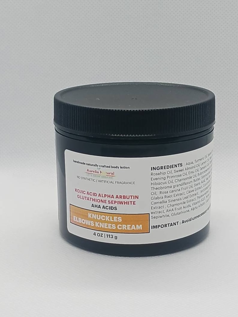 Op de afbeelding: Een zwarte pot Aurelia Natural Knuckles, Elbows, Knees Cream. Het etiket bevat de tekst "KOJIC ACID ALPHA ARBUTIN GLUTATHIONE SEPIWHITE AHA ACIDS" en "4 OZ | 113 g". De cr&egrave;me is een handgemaakte bodylotion zonder synthetische geurstoffen.