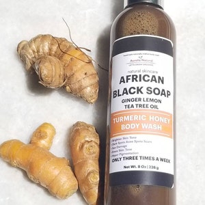 Puede incluir: Una botella de African Black Soap Turmeric Honey Body Wash con raíces de jengibre y cúrcuma. La etiqueta enumera ingredientes y beneficios. La botella contiene 226 g de producto.