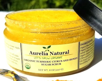 Può includere: Un barattolo di scrub allo zucchero biologico Aurelia Natural con curcuma, agrumi e miele. Il barattolo contiene uno scrub giallo brillante e ha un coperchio nero. L'etichetta recita "Peso netto 227 g" ed elenca gli ingredienti.