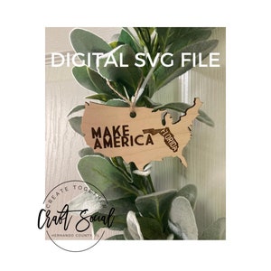May include: Wooden cutout of the United States with the text "Make America" and a smaller cutout of Florida with the text "Florida". The cutout is hanging from a green leafy garland. The text "Create Together Craft Social Hernando County, FL" is visible below the cutout.