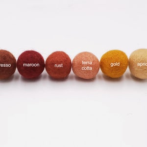 May include: Six felt balls in various shades of brown, orange, and yellow. The balls are labeled "espresso", "maroon", "rust", "terra cotta", "gold", and "apricot".