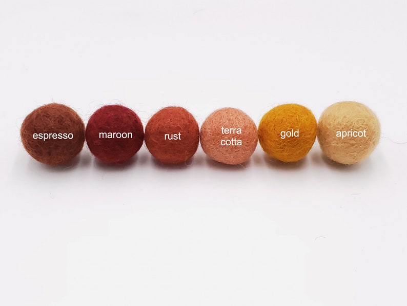 May include: Six felt balls in various shades of brown, orange, and yellow. The balls are labeled "espresso", "maroon", "rust", "terra cotta", "gold", and "apricot".