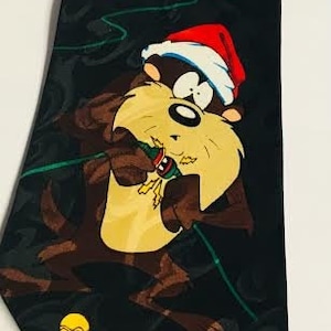 May include: A black silk tie with a Christmas theme featuring Bugs Bunny and Daffy Duck. Bugs Bunny is dressed as a Christmas tree with lights and ornaments. Daffy Duck is holding a Christmas stocking. The tie has a green, red, yellow, and blue color scheme.