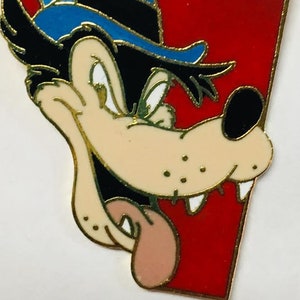 May include: A cartoon wolf with a mischievous grin, wearing a blue and black hat, is depicted on a red background. The wolf's tongue is sticking out, and its eyes are wide open. The image is a pin or patch.