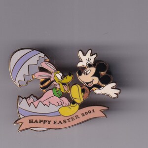 May include: A gold-tone pin featuring Mickey Mouse and Pluto. Pluto is wearing bunny ears and is inside a purple and white Easter egg. Mickey is holding the egg and smiling. The pin has a banner that reads "Happy Easter 2001".
