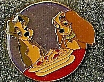 以下が含まれることがあります： ディズニーのキャラクター、レディとトランプがスパゲッティの皿を共有している丸いピン。ピンは金色で、背景は紫です。
