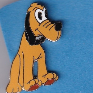 May include: A yellow and black cartoon dog pin with big eyes and a black nose. The dog is standing on all fours and has a friendly expression.