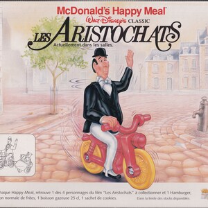 Puede incluir: Anuncio de McDonald's Happy Meal con un personaje de "Los Aristogatos" de Disney montado en una moto roja. La imagen incluye texto en francés y una pequeña ilustración del personaje con gatos. El fondo representa una escena de calle europea.